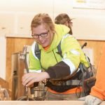 female apprentice smiles as she learns carpentry